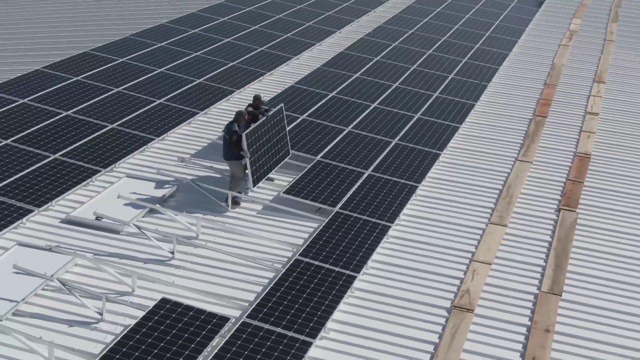 Un equipo de tres hombres sujetando un panel solar durante una instalación que beneficia a Costa Rica de varias maneras.